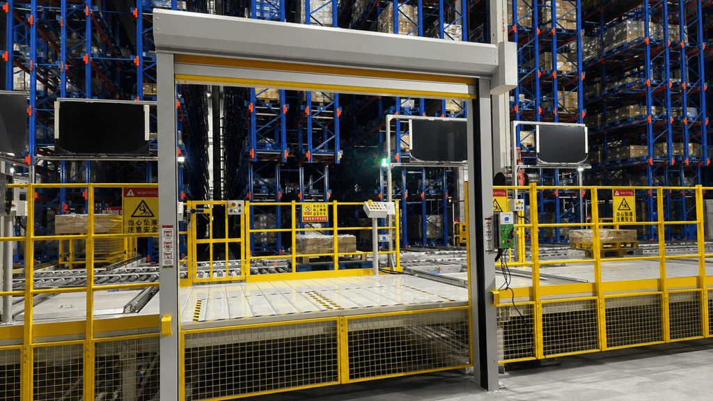 Puerta rápida industrial abierta en un sistema de manejo de materiales de almacén automatizado