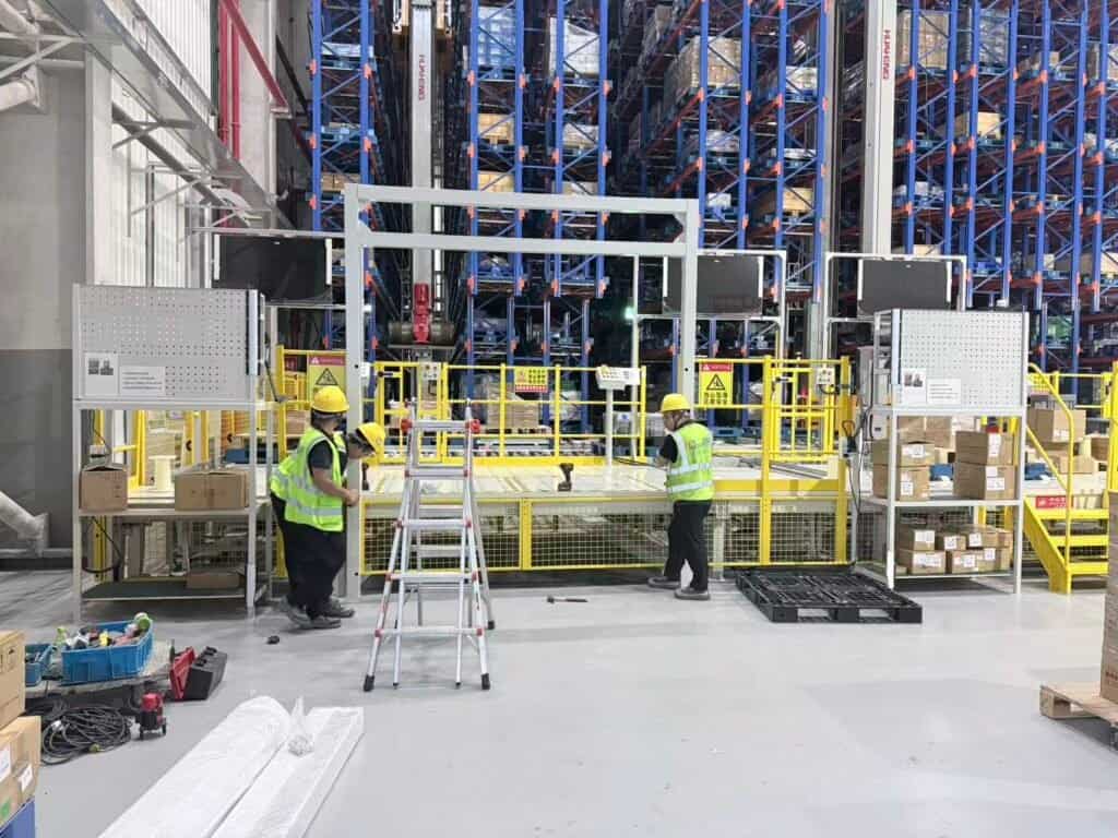 Técnicos instalando un marco de puerta industrial de alta velocidad dentro de un almacén automatizado