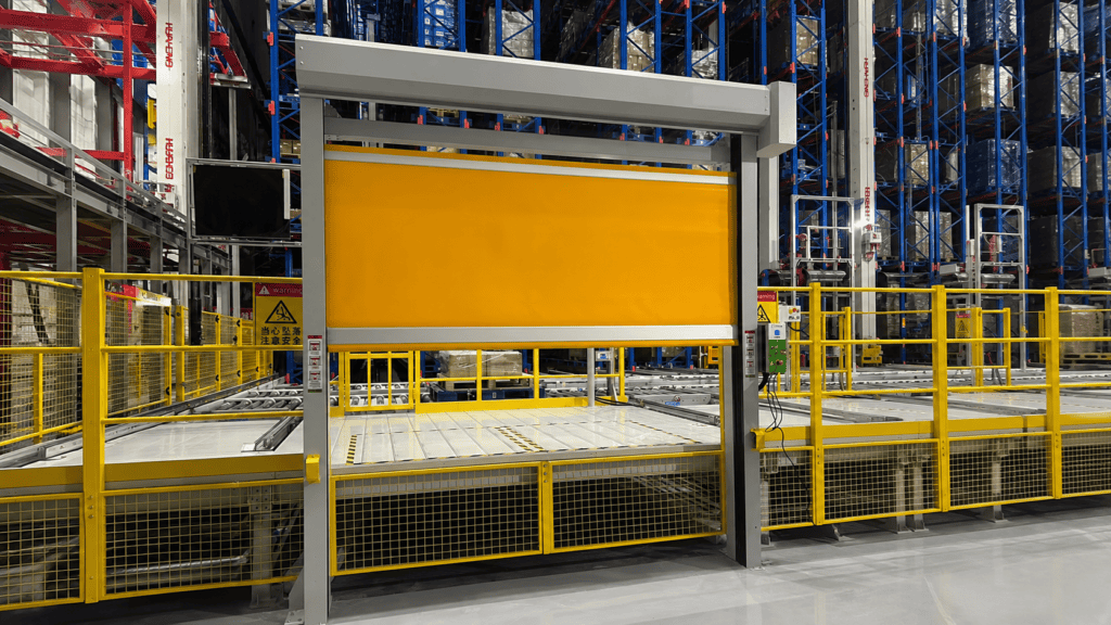 Puerta rápida de seguridad amarilla para línea de transportadores instalada en un área de transportadores de almacén automatizado