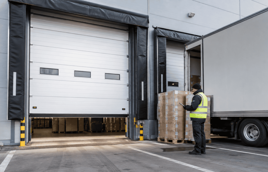 High speed sectional door in a logistics facility with a worker loading pallets.